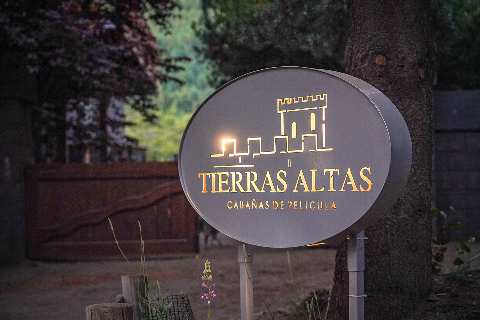 Cartel iluminado de Tierras Altas, cabañas de película, al atardecer