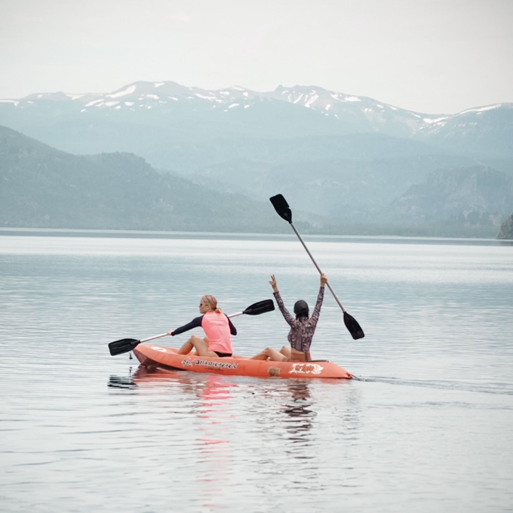 Kayak celebrando en el lago Meliquina con las montañas de fondo
